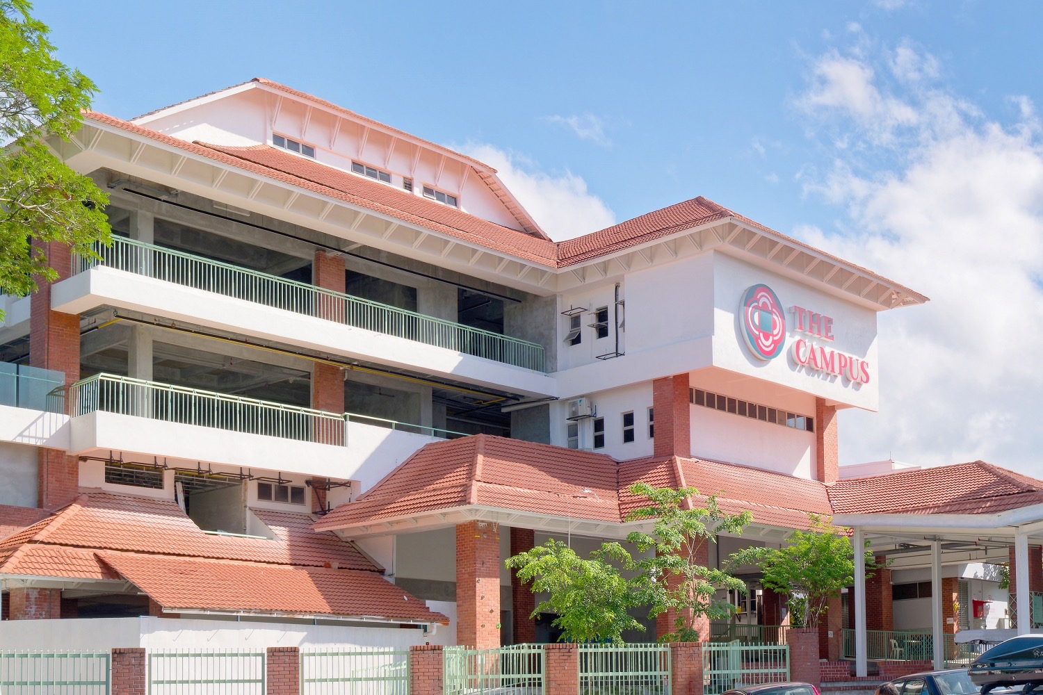 The Campus Ampang exterior, terracotta roofs and red brick columns under a blue sky